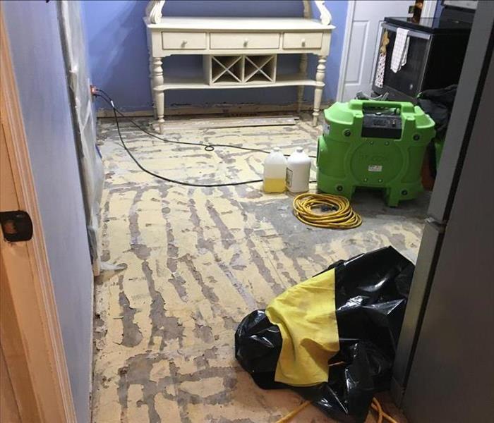 Ripped flooring with a green air mover sitting on top.
