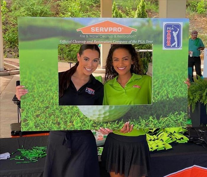 SERVPRO girls in golf uniform holding up a golf tournament sign