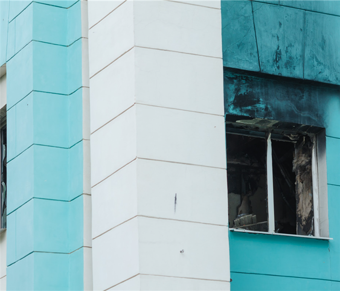 Broken window of a building with smoke , sky blue and white building, 